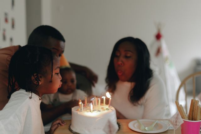 Happy Family with Children Blowing Candles on Birthday Cake