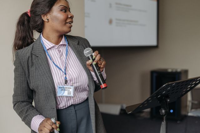Woman in Gray Suit Holding Microphone